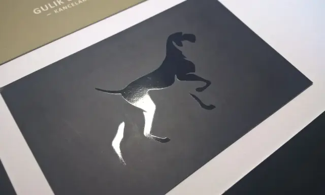 Elegancka wizytówka z psem w skoku, wykonana techniką lakierowania wybiórczego. Błyszczący pies kontrastuje z matowym tłem.