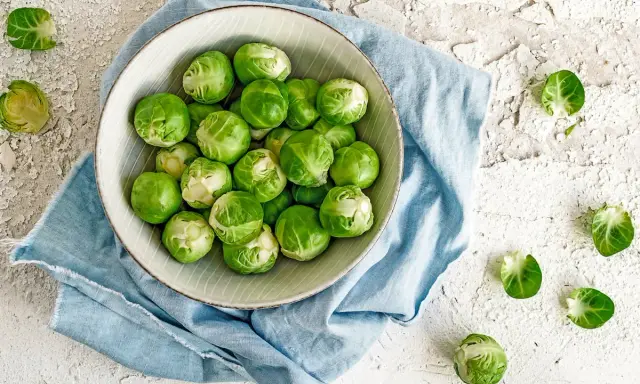 Un bol de choux de Bruxelles frais, prêts à être cuisinés. Ces légumes verts sont parfaits pour une alimentation saine, loin de toute maladie choux de bruxelles.