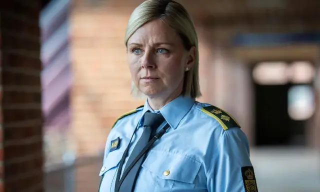 En kvinna i uniform från uniformen serie, med blå skjorta och slips, blickar ut.