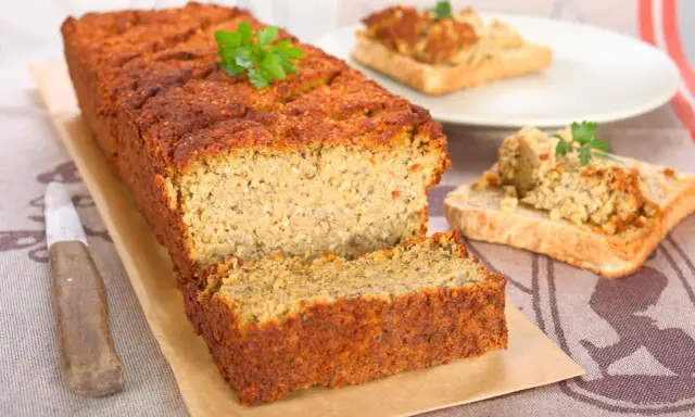 Pyszny pasztet z soczewicy, idealny na kanapki. Obok kromki tostów z pasztetem i gałązką natki.