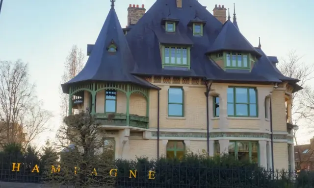 La villa Demoiselle Pommery, une demeure Belle Époque aux toits d'ardoise et aux ornements verts, se dresse fièrement.
