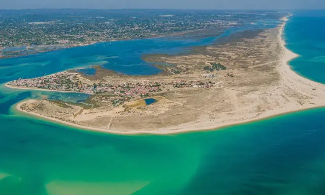 Luftaufnahme der Faro Inseln mit türkisfarbenem Wasser, Sandstränden und einer kleinen Stadt.