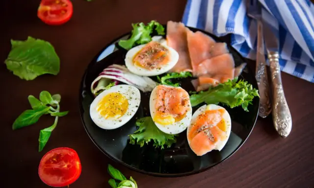 Jajka na twardo z łososiem i sałatą, idealne na dietę low carb. Pomidorki i zielenina dopełniają danie.