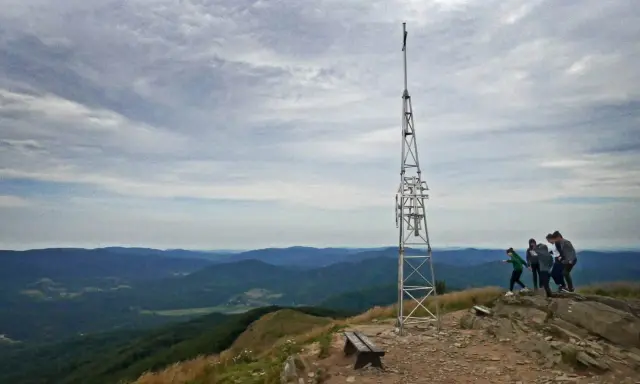 Grupa turystów podziwia widok na góry z wieżą telekomunikacyjną. Smerek z Wetliny wita wędrowców.