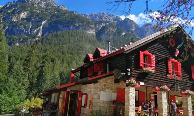 Rifugio con forni di sopra, circondato da boschi e montagne imponenti.