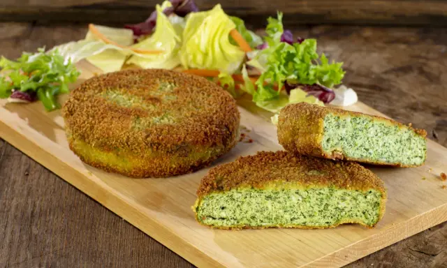 Deliziose spinacine fatte in casa, dorate e croccanti, servite con un'insalata fresca su un tagliere di legno.