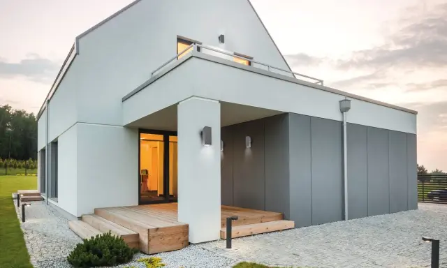 Nowoczesne oświetlenie elewacji podkreśla architekturę domu. Lampy ścienne i stojące tworzą przytulną atmosferę.