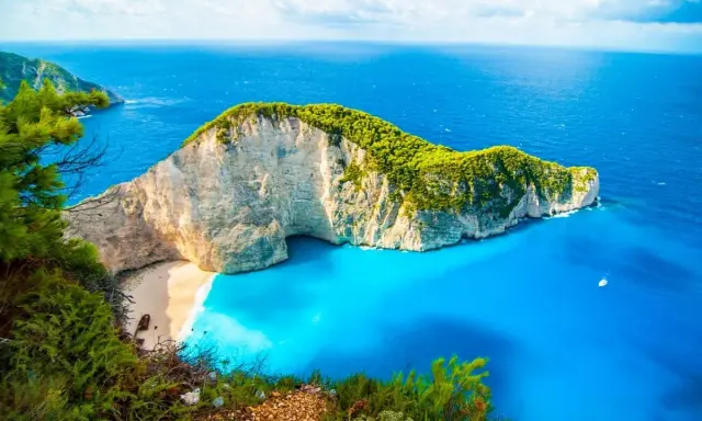 Widok na Navagio Beach, jedną z najpiękniejszych greckich atrakcji. Białe klify, turkusowa woda i zielona roślinność tworzą rajski krajobraz.