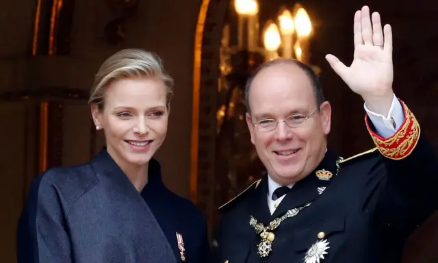 Charlene, furstinna av Monaco, ler vid sidan av prins Albert. Han vinkar glatt till publiken.