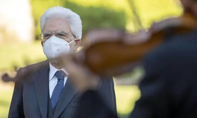 Un uomo con mascherina bianca ascolta un violinista. Un bel tacer non fu mai scritto, ma la musica parla.