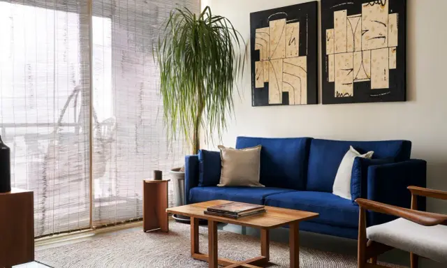 Salones muy pequeños con encanto: sofá azul vibrante, mesa de centro de madera, planta frondosa y arte abstracto en las paredes.
