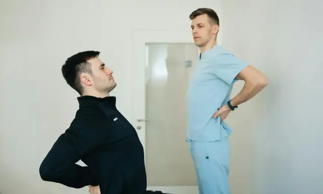 Fizjoterapeuta pomaga pacjentowi z chorobą Scheuermana w ćwiczeniach poprawiających postawę.