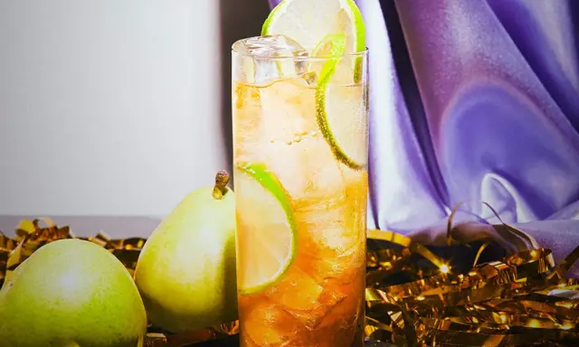 En uppfriskande drink med päron och lime, perfekt för svenska drinkar. Guldfärgad konfetti och lila tyg skapar festlig stämning.