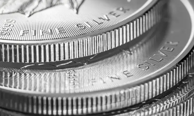 Zbliżenie na stos monet z napisem "FINE SILVER". Błyszczące srebro, idealne na prognozy inwestycyjne.