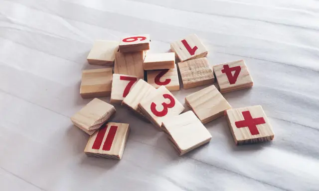 Drewniane klocki z cyframi 1, 2, 3, 4, 6, 7, 11 i znakiem plus. Jak wyliczyć numerologię?