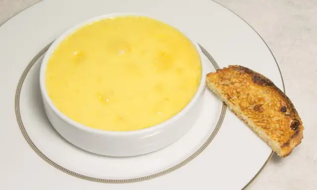 Crème onctueuse à la noix de coco, servie dans un bol blanc avec une tranche de pain grillé.