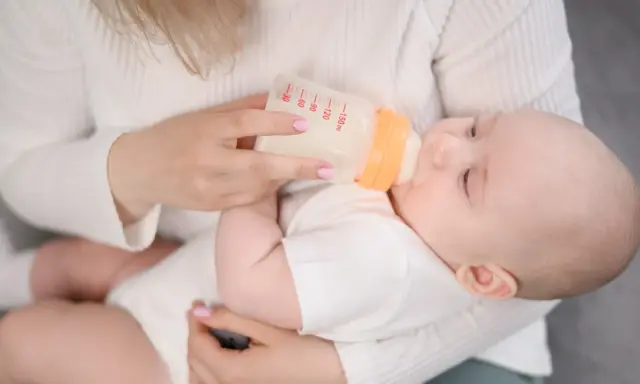 Mama karmi dziecko butelką. Choć mleko Bebilon wycofane, maluch spokojnie pije.