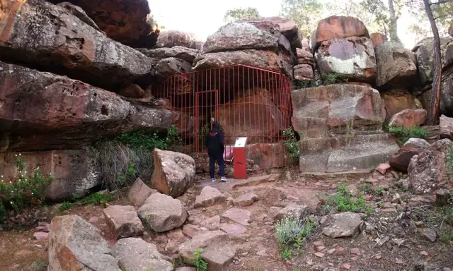 Persona observa pinturas rupestres albarracín, protegidas por una valla roja.