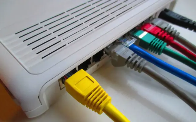 Router z podłączonymi kolorowymi kablami sieciowymi.
