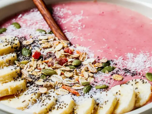 En rosa smoothie bowl med bananskivor, granola, pumpafrön, chiafrön och kokosflingor. En perfekt start på dagen!
