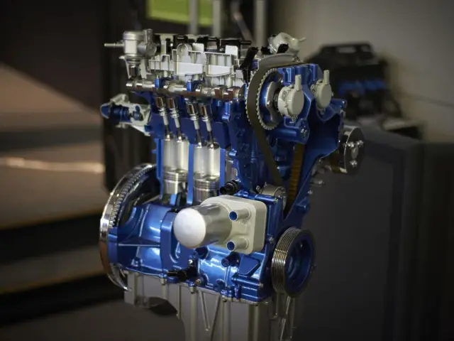 Przekrój silnika 1.0 Ecoboost w kolorze niebieskim, z widocznymi tłokami i paskiem rozrządu.