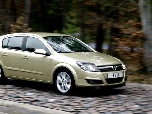 Złoty Opel Astra 1.7 CDTI w ruchu, na tle rozmytego lasu.
