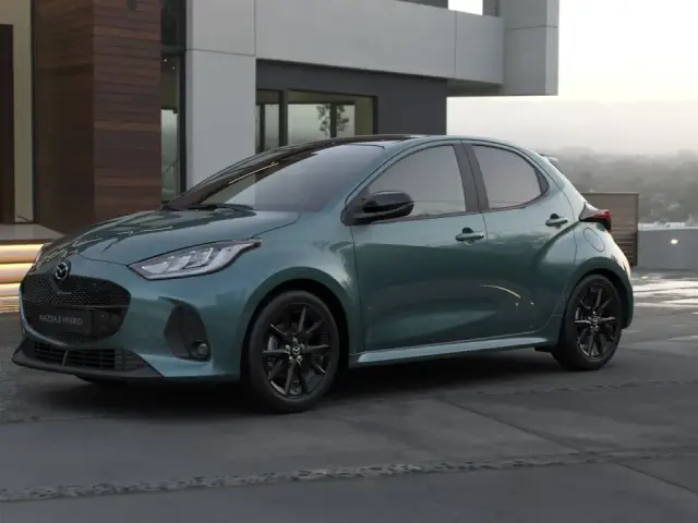 Elegancka, zielona Mazda 2 Hybrid stoi przed nowoczesnym domem.