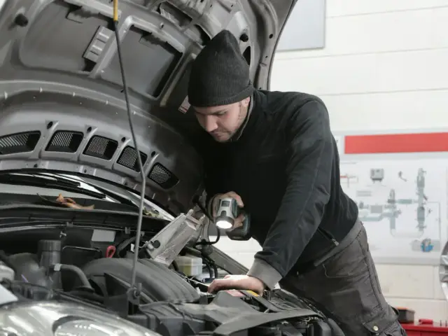 Mechanik z latarką bada silnik 1.6 TDI.