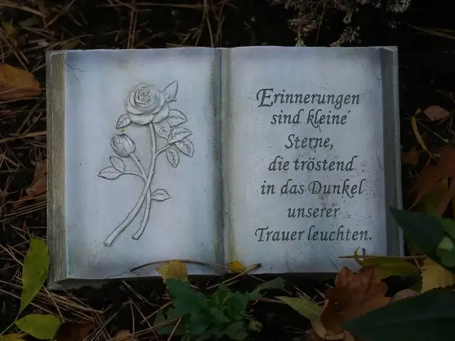 Kamienna księga z różą i niemieckim cytatem, piękny przykład epitafium.