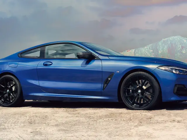 Błękitne BMW 840i z czarnymi felgami na tle pustynnego krajobrazu i gór.