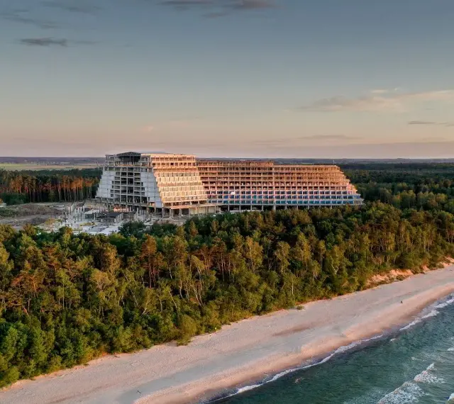 Ogromny, niedokończony hotel, który ma być największym hotelem w Polsce, góruje nad lasem i plażą o zachodzie słońca.