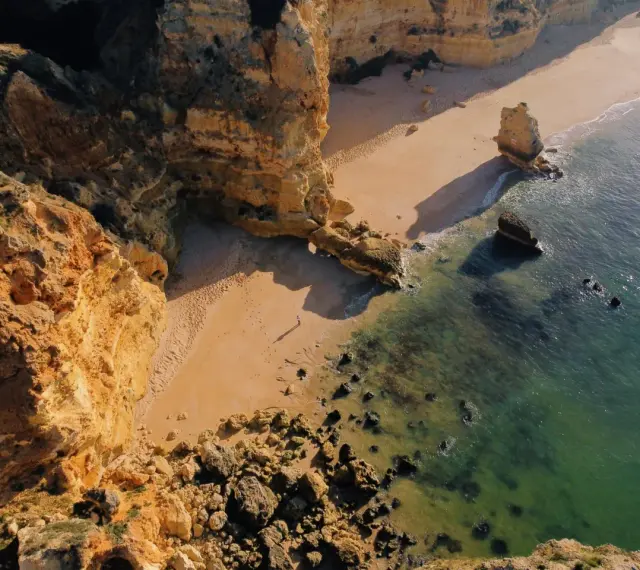 Malownicze klify i piaszczysta plaża w Portugalii. Morze o turkusowym odcieniu obmywa skaliste wybrzeże, tworząc idealne miejsce na spacer.