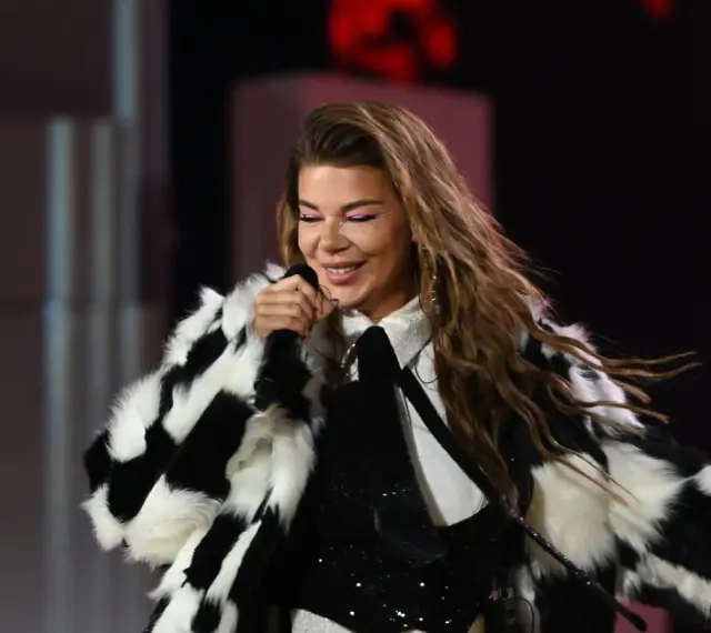 Edyta Górniak w szachownicznym futrze, z różowym makijażem oczu, śpiewa na scenie. Pamiętny występ na Eurowizji.