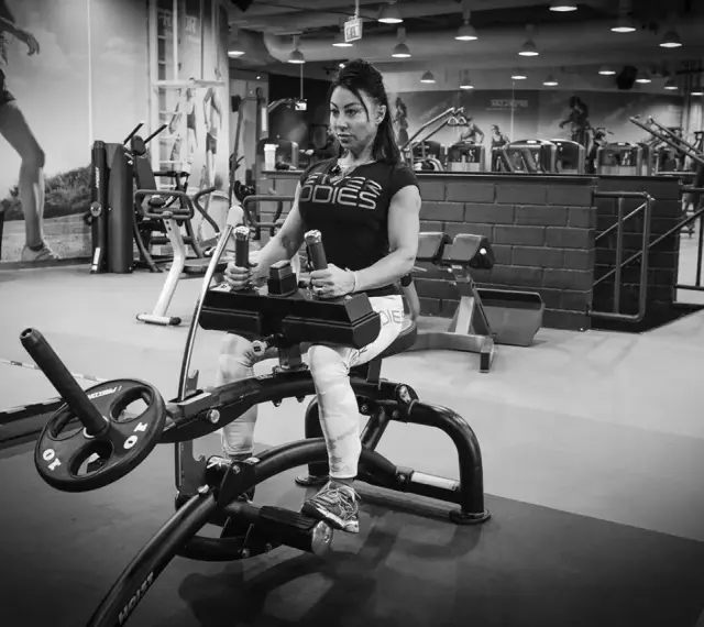 Kvinna tränar sittande vadpress på gym.