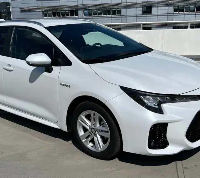 Biały Suzuki Swace Hybrid na parkingu. Elegancki kombi z nowoczesnym designem, gotowy na każdą podróż.