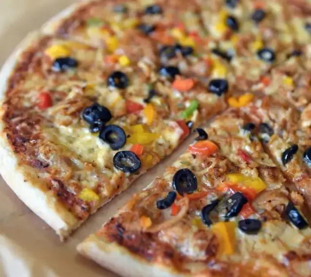 Pyszna pizza z kurczakiem, oliwkami i kolorową papryką. Wiele rodzajów pizzy może się równać z jej smakiem.