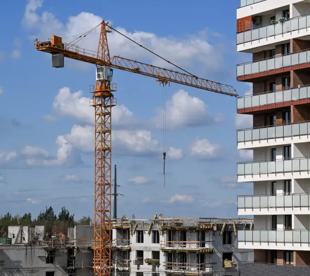 Budowa nowego osiedla przez lex deweloper. Żuraw budowlany pracuje przy nowoczesnym bloku mieszkalnym.