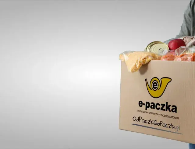 Mężczyzna niesie kartonowe pudełko z produktami spożywczymi, które jest częścią elektronicznej paczki żywnościowej.
