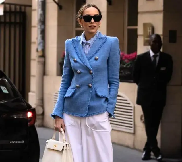 Elegancka kobieta w niebieskiej marynarce i białych spodniach, gotowa na sesję lookbook.