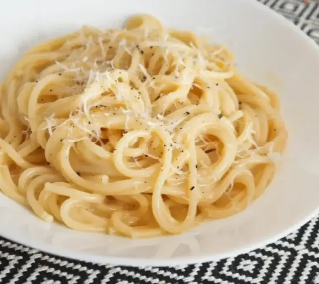 Pyszne spaghetti carbonara przepis na talerzu, posypane parmezanem i świeżo mielonym pieprzem.