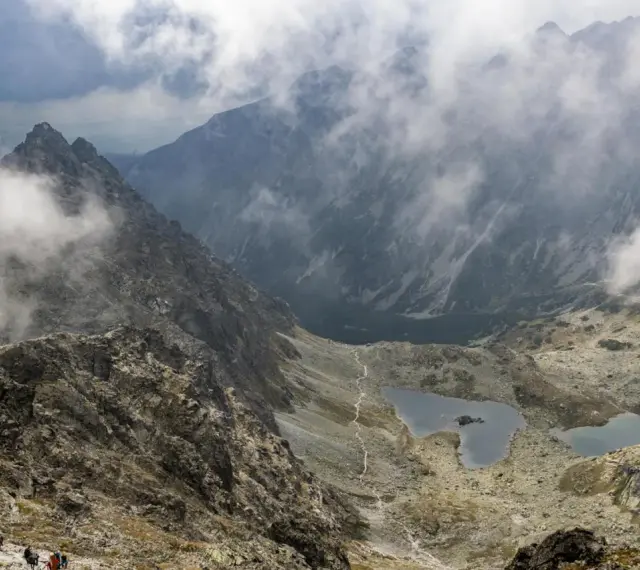 Widok na szlak turystyczny i jeziora w Tatrach, w oddali majaczy schronisko pod Rysami.