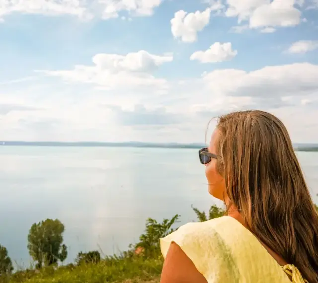 Kobieta w okularach podziwia rozległy Balaton, zachwycona czystością wody i błękitem nieba.