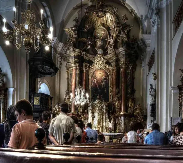Wnętrze kościoła z bogato zdobionym ołtarzem. Ludzie siedzą w ławkach, słuchając kazania. Czy to czas na gorzkie żale?