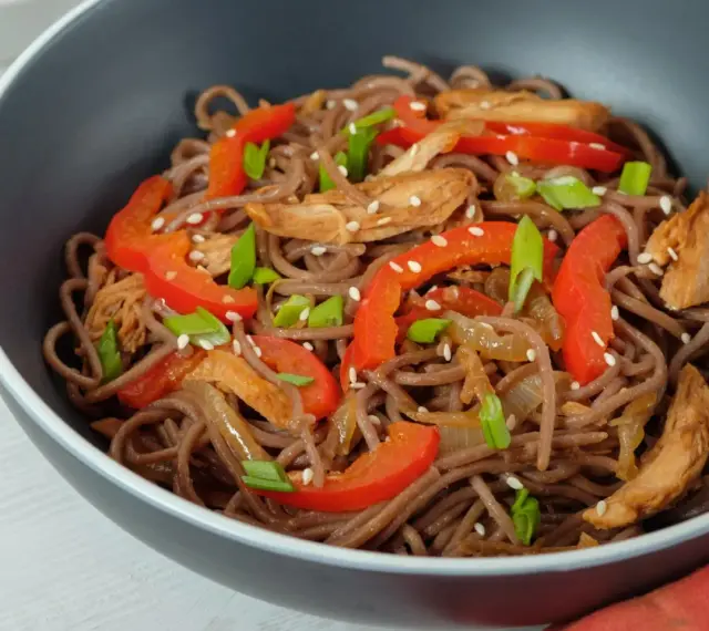 Makaron soba przepis: danie z makaronem gryczanym, kurczakiem, papryką i szczypiorkiem, posypane sezamem.