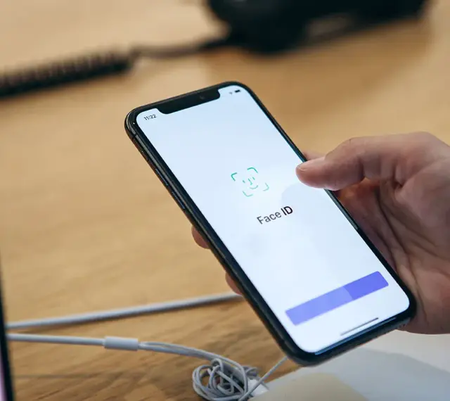 Dłoń trzyma smartfon, na ekranie którego wyświetla się komunikat "Face ID". Wygląda na to, że Face ID nie działa.