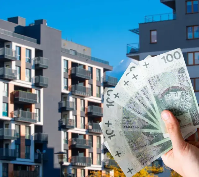 Dłoń trzyma banknoty 100 zł na tle nowoczesnych bloków mieszkalnych. Czy to wyjaśnia, dlaczego ceny najmu w Warszawie i Krakowie przestały rosnąć w pierwszym kwartale 2026?