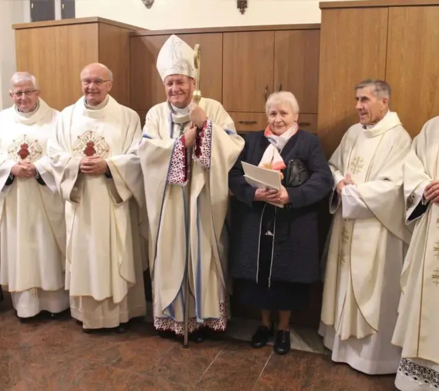 Uroczystość z udziałem biskupa i duchownych. Wśród nich stoi kobieta, która jest wdową konsekrowaną.