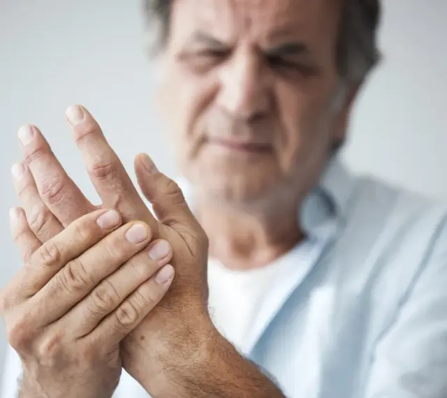 Mann hält seine Hand, da seine Finger schmerzen beim Beugen.