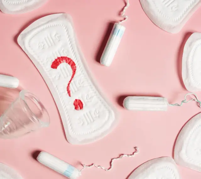 Brązowe plamienie zamiast okresu? Podpaski, tampony i kubeczek menstruacyjny na różowym tle symbolizują niepewność.