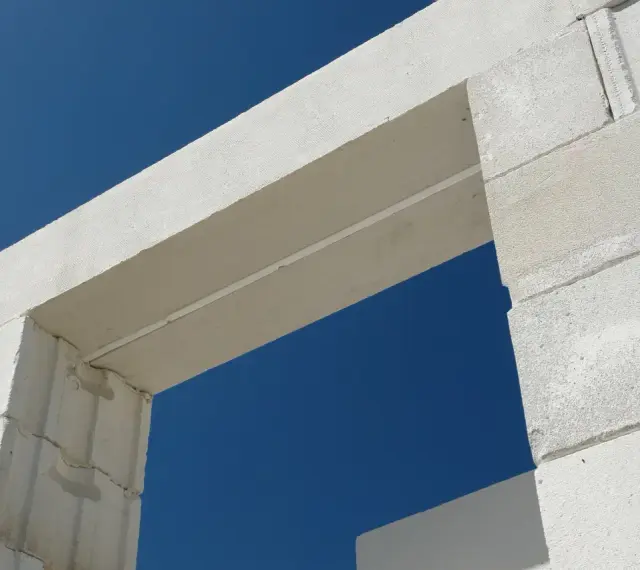 Białe nadproże nad drzwiami 90, wykonane z bloczków z betonu komórkowego, na tle błękitnego nieba.
